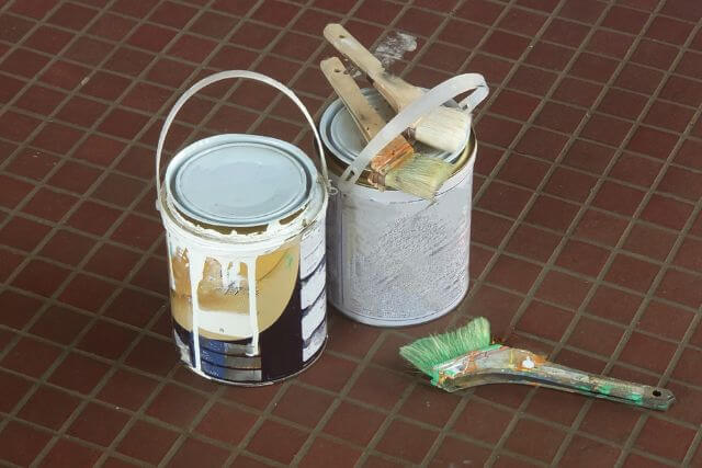 レンガの床に置かれたペンキ缶と刷毛